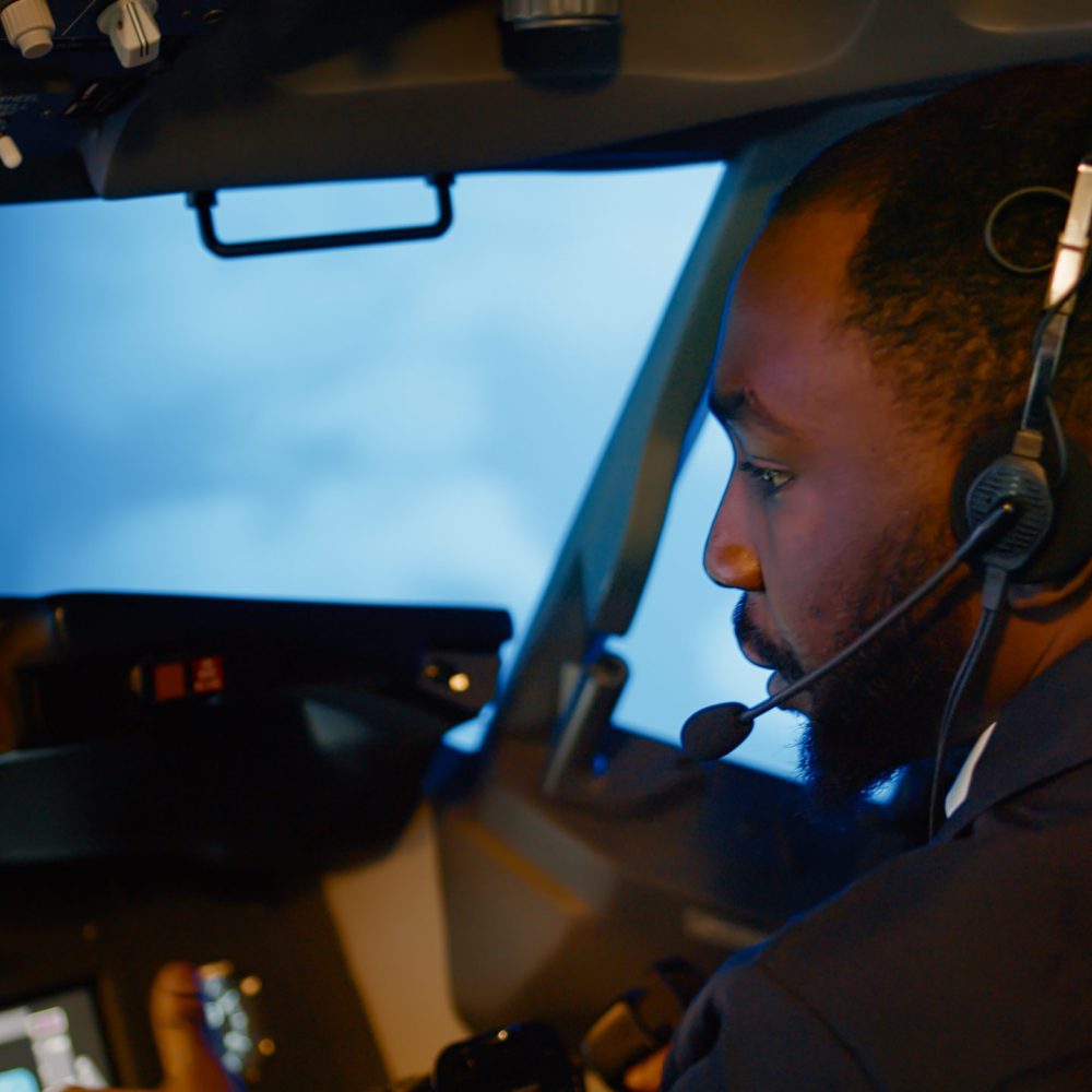 African american copilot using airplane command to fly plane, throttling power engine to takeoff. Control panel navigation with radar compass and dashboard in captain cabin. Close up.